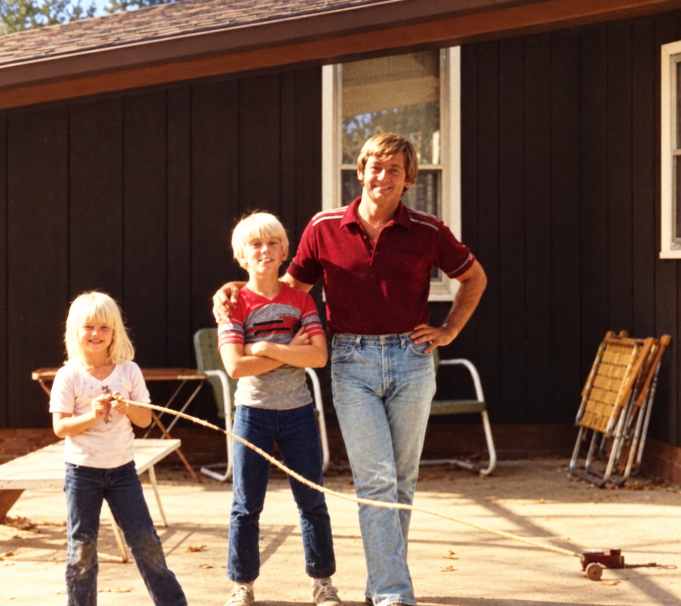 A restored childhood photo of Kalan with his dad and stepsister, standing outside together.